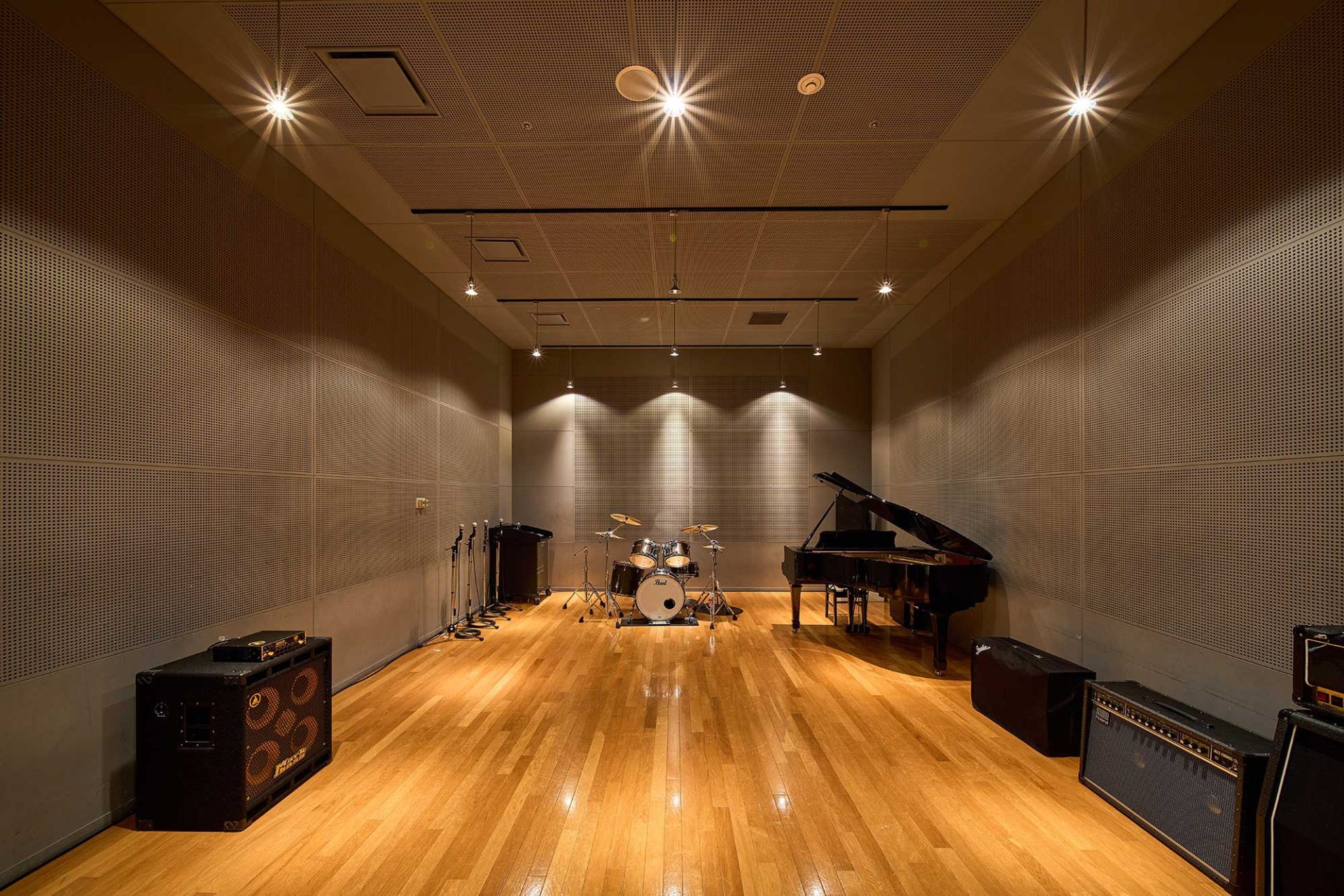 写真：スタジオ内にグランドピアノとドラムセットがある。アンプやスピーカー、マイクスタンドも揃っている。